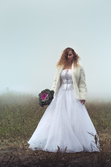 Fototapeta na wymiar Bride on the field in the fog