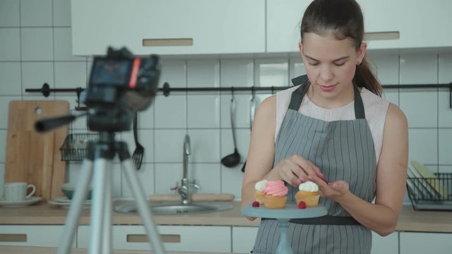 Confectionery blog. Housewife cooked cakes, put them on a stand and photographed them to make a post in blog. Pastry vlog. Confectioner decorates the capcake and then takes pictures on the smartphone