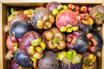Fresh mangosteen in wooden box. Tropical fruit. Queen of fruit. Top view.