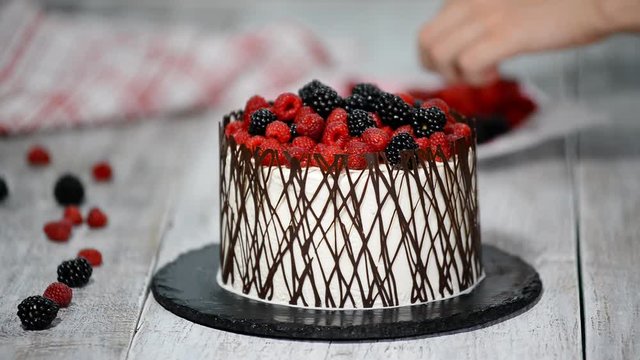 Decorate the cake with berries and chocolate. Homemade cake.