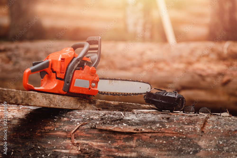 Poster close-up of chainsaw lies on sawn wood sawmill. concept logging industry