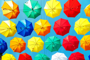 Multicolored floating umbrellas against the blue sky.