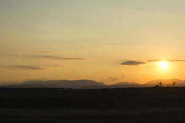 sunset on a field with mountains in backround