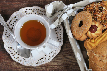 various cookies and biscuits baked at home in a container with polka dots and tea in a retro cup