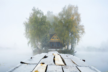 wooden pathway to old farm house in foggy morning of autumn day