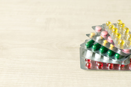 Pharmaceuticals antibiotics pills capsule medicine.  Stack  of different colorful antibacterials pills and capsule on wooden background
