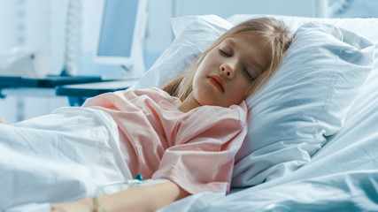 Obraz na płótnie Canvas Cute Little Sick Girl Sleeps on a Bed in the Children's Hospital. Modern Pediatric Ward with Top Quality Health Care.
