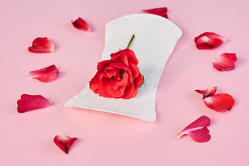 Fototapeta na wymiar Sanitary napkin and flower on pink background