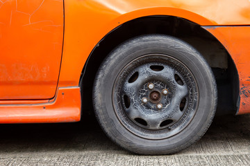 Old car wheels and old tires. It need to be replaced. This may cause an accident on the road.