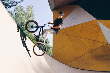 BMX rider makes a TAilwhip trick. Young man doing tricks in the air on a BMX bike. BMX freestyle