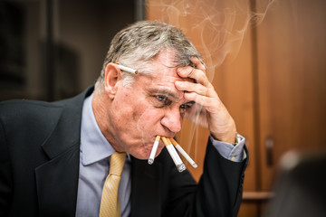 Nervous businessman smoking many cigarettes at once