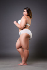 Plus size model in lingerie, fat woman on gray background, overweight female body