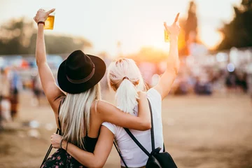 Poster Twee vriendinnen bier drinken en plezier hebben op muziekfestival.Achteraanzicht © Astarot