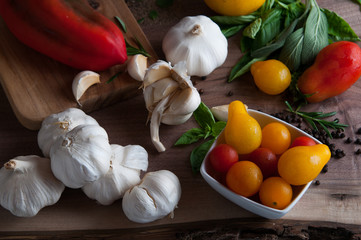 tomatoes garlic peppers and herbs for salsa on a wooden back ground