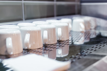 Fototapeta na wymiar clean white cups stand on the bar in a restaurant on a silver dryer. white coffee mug. tea utensils