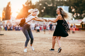 Two female friends spinning around and having fun at music festival