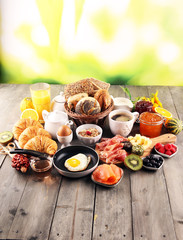 breakfast on table with bread buns, croissants, coffe and juice.