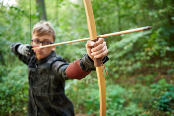 boy teenager has training, shoots a wooden bow in the forest
