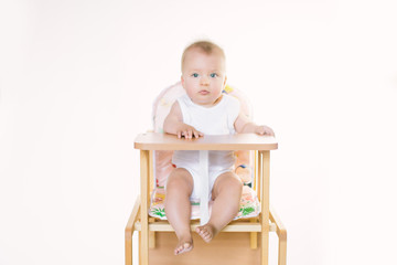 The baby is sitting on the chair and is preparing for feeding.