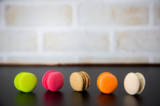 macarons on black floor and brick wall background. candy, bakery and kitchen. frence dessert. luxury sweets of france.image for background, wallpaper and copy space,