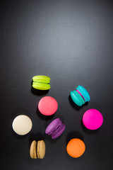 macarons on black floor and brick wall background. candy, bakery and kitchen. frence dessert. luxury sweets of france.image for background, wallpaper and copy space,