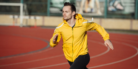 Sportsman running on a stadium, sprinter man on red tracks lanes in high speed