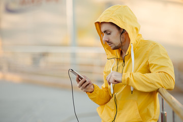 Runner man athlete at outdoor stadium listening to music with his earphones. Respite before race.