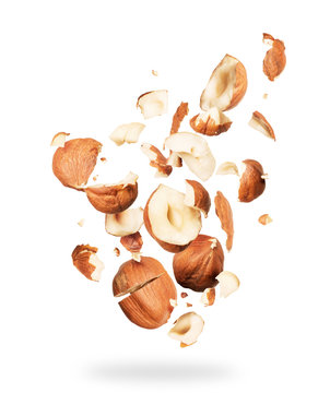 Hazelnuts crushed into pieces, frozen in the air on a white background