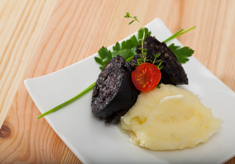 Blood sausage with mashed potato served at plate with greens