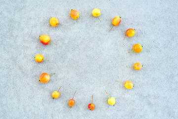 Fototapeta na wymiar Circle of wild cherry apples on concrete background