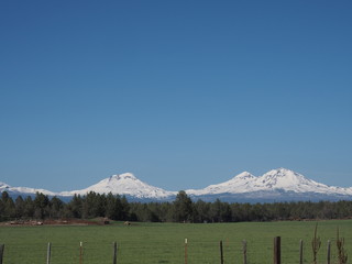 The beautiful Three Sisters in Oregon's Cascade Mountain Range seen from a farm field in Central Oregon