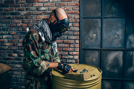 Man in gas mask touching bomb while standing against brick wall