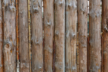 A fence made from brown round vertical pine logs. Natural log background
