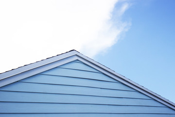 Blue shiplap house exterior against blue cloudy sky