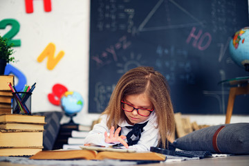 Fototapeta premium Smart little schoolgirl with digital tablet in a classroom. Child in an elementary school. Education and learning for kids.