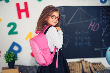 Little girl with a pink school backpack. The concept of school, study, education, friendship, childhood.