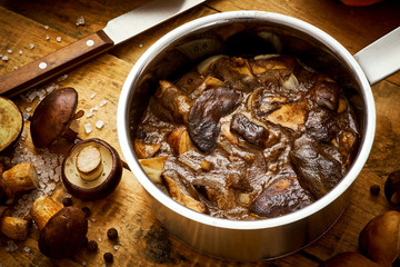 delicious brown mushrooms stewed in sour cream in a saucepan on a wooden table