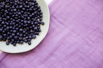 Blueberries in a plate on a table with a colored cloth.