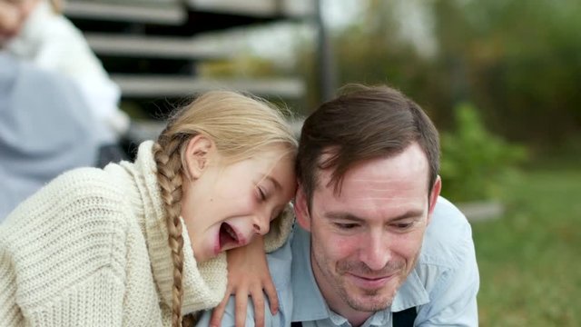 Young Girl Sitting Hugging Her Father and Reading a Book.