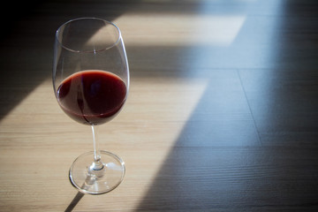 red wine in wine glass, placed on the floor with window light and shadow. scenery and romantic concept. dramatic, scenery in the evening.