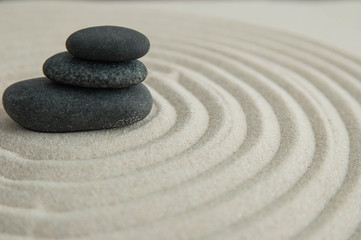 Pyramids of gray zen stones on the sand with wave drawings. Concept of harmony, balance and meditation, spa, massage, relax