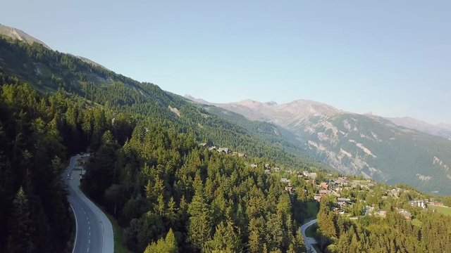 Alps mountains landscape wilderness in summer aerial drone footage climbing up with forest and village