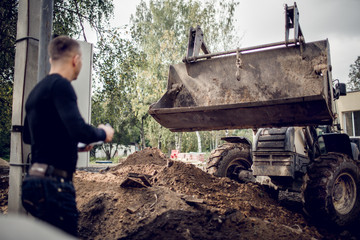 Man with plan of working in his hand is as a customer  on the construction site and looks the...