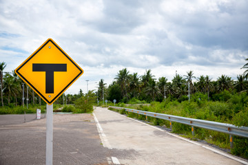 three intersection yellow traffic sign on wayside with cloudy sky, perspective road. image for background, copy space, add text.