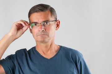 Fototapeta premium Portrait of senior man in eyeglasses on gray background