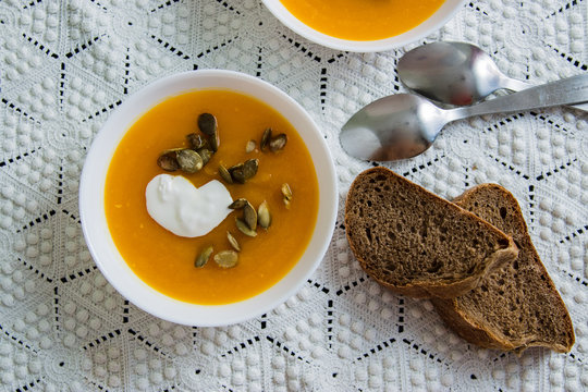 Pumpkin soup with cream, seeds, bread on grunge black background. Top view