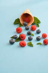 An ice cream cone with blueberries, raspberries and mint on a colorful background as a symbol of a refreshing summer fruity ice cream