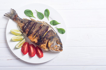 Fried fish dorado with lime , tomatoes and spinach