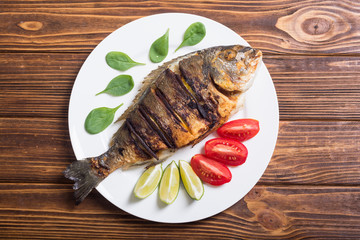 Fried fish dorado with lime , tomatoes and spinach