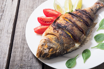 Fried fish dorado with lime , tomatoes and spinach